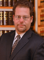 A man in suit and tie standing next to some books.